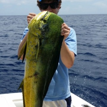 Person holding a large fish on a boat in open water.