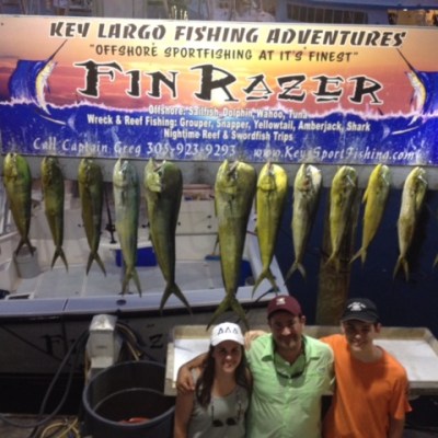 Group posing under a fishing sign with caught fish hanging above them.