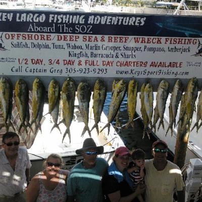 Group posing with fish catch under Key Largo fishing sign.